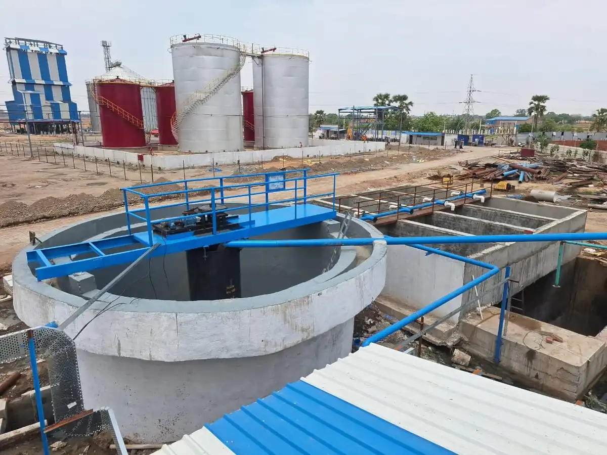 Clarifier with drive bridge and treatment tanks under construction at ESE, with distillery storage tanks behind